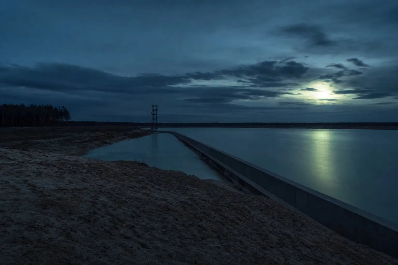 Überleiter zwischen zwei Tagebauseen mit Aussichtsturm am Horizont in der Dämmerung