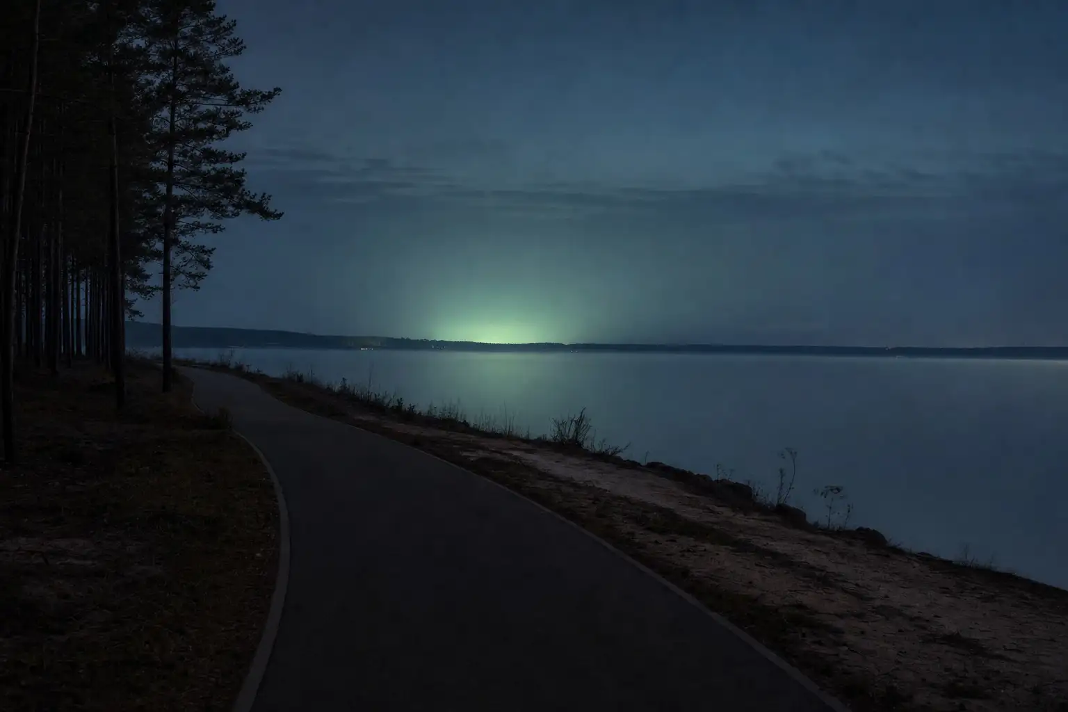 Asphaltierter Radweg am Ufer eines Sees im Lausitzer Seenland in der Abenddämmerung